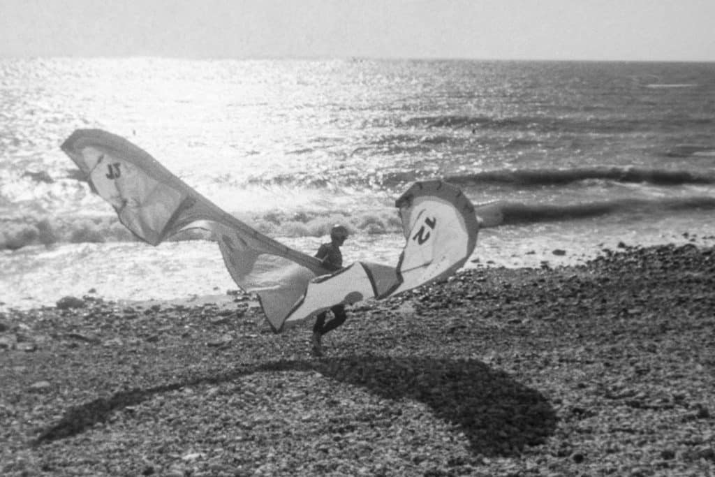 Kite Surfeur tel un oiseau déploie sa voile et marche vers la mer avec sa sa planche sur le bord de la plage du Havre
