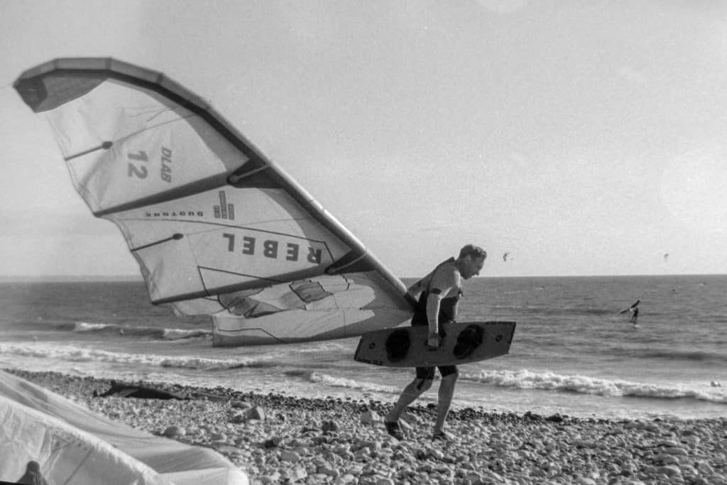 Kite Surfeur marche vers la mer avec sa voile et sa planche à la main sur le bord de la plage du Havre